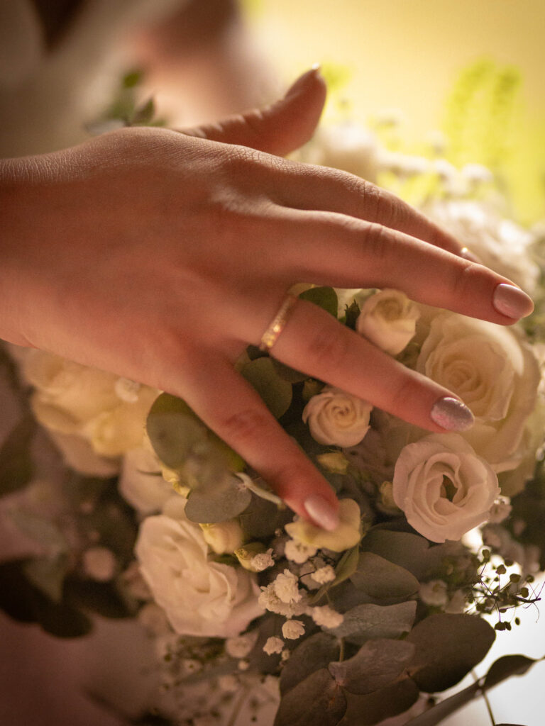 Hand der Braut mit Ehering auf dem Brautstrauß
